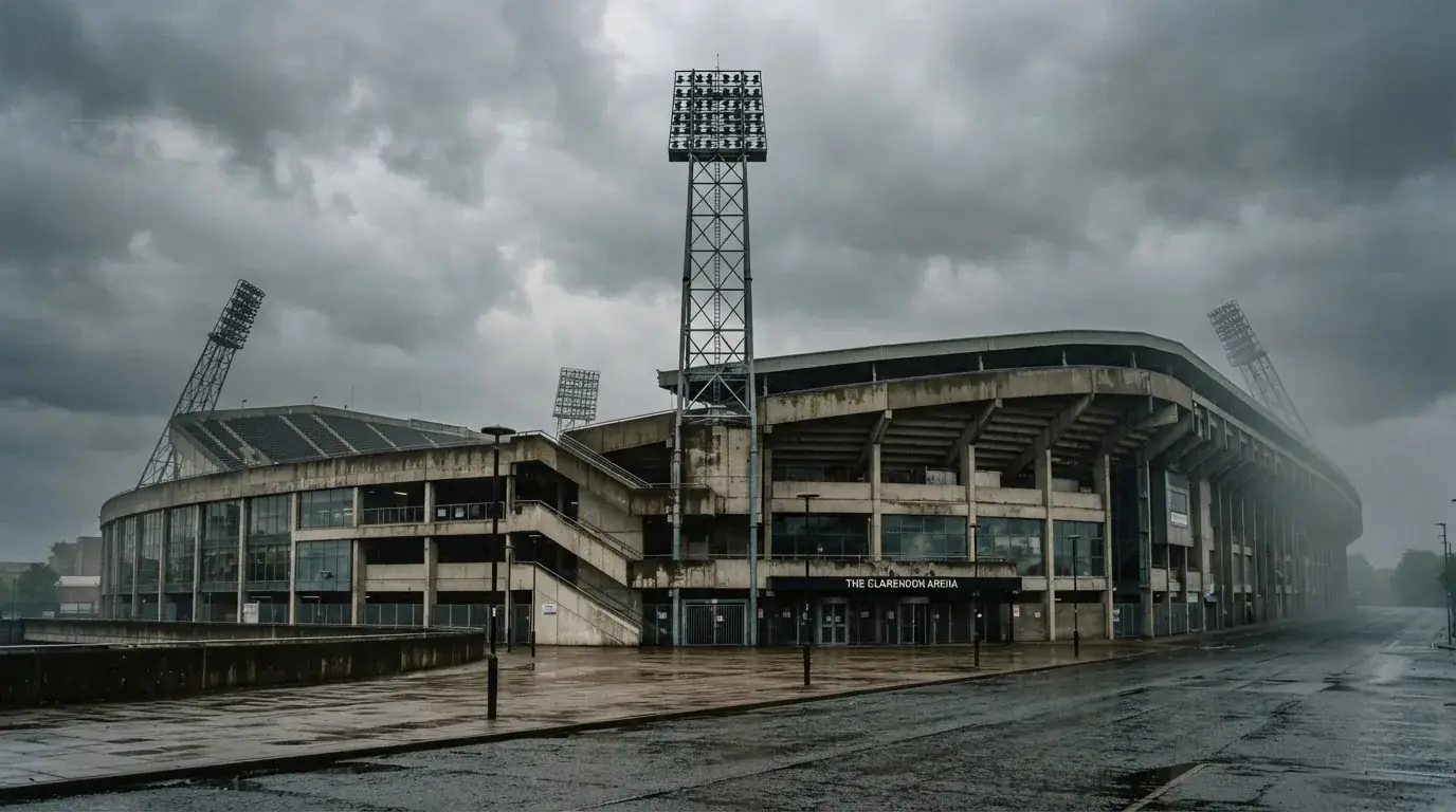 Ein leeres Stadion von außen, hohe Flutlichtmasten vor einem grauen Himmel mit Regenwolken.